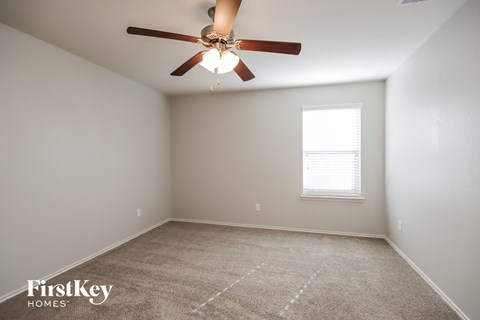 an empty room with a ceiling fan and a window