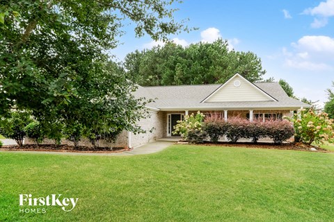 a white brick house with a lawn and trees