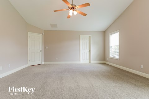 the master bedroom has a carpeted floor and a ceiling fan