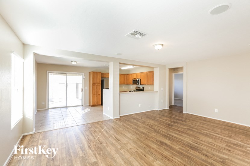 a spacious living room with wood flooring and a kitchen
