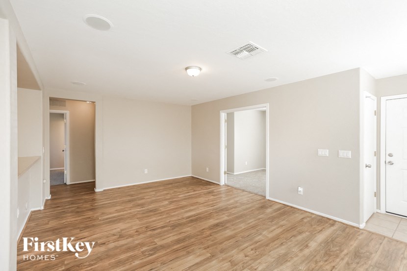 a spacious living room with wood flooring and white walls