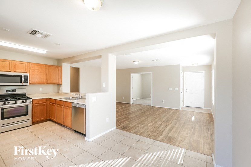 an empty kitchen and living room with wood flooring and appliances