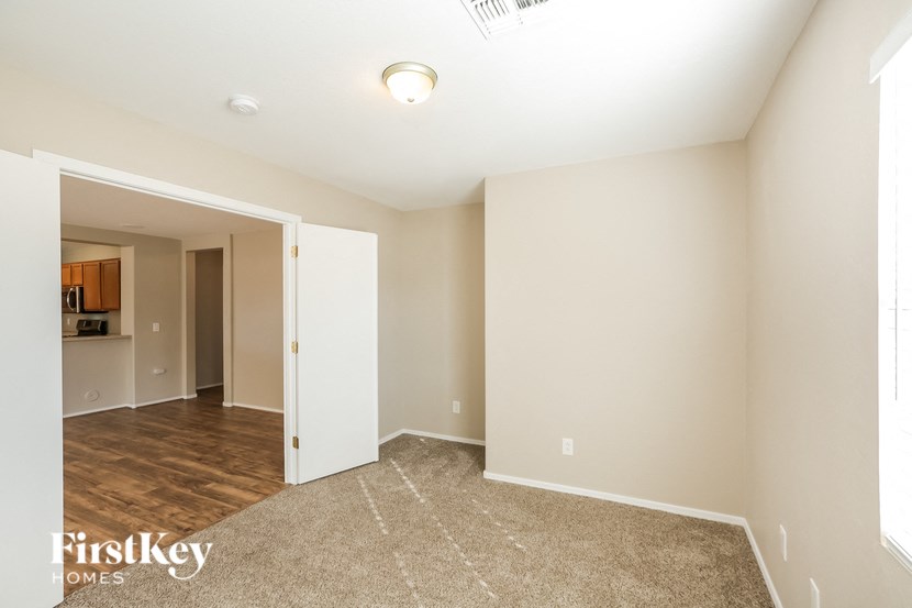 a spacious living room and dining room with wood flooring and white walls
