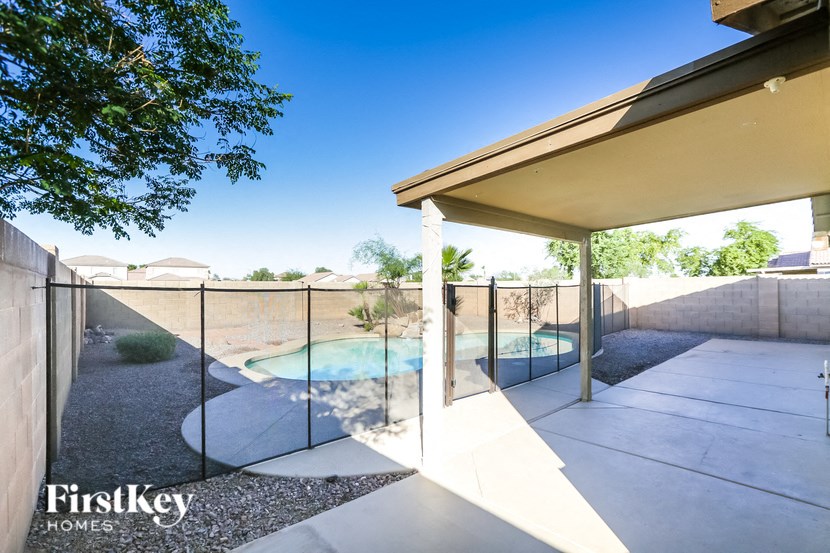 a backyard with a pool and a house with a glass fence