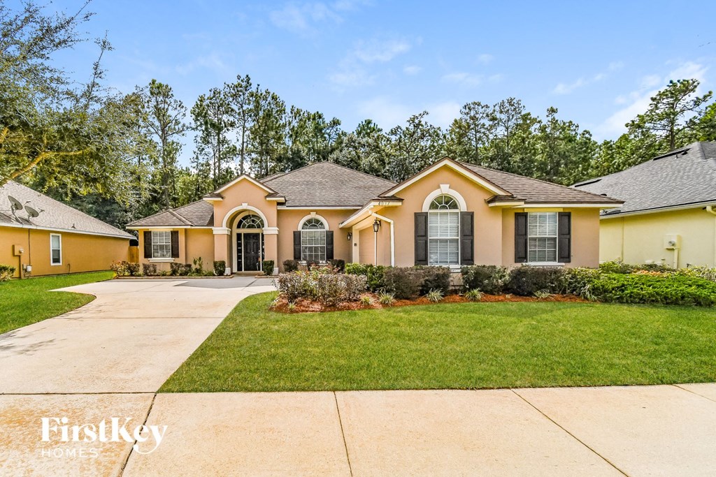 a yellow house with a driveway and a lawn