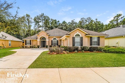 a yellow house with a driveway and a lawn