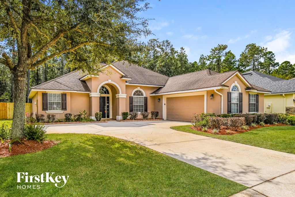 a yellow house with a driveway and a tree