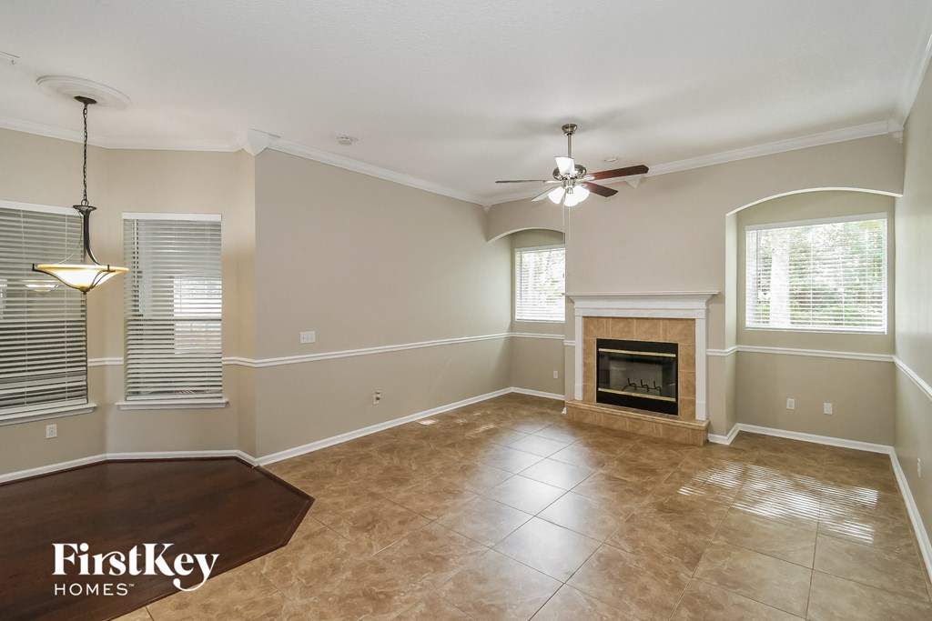 an empty living room with a fireplace and a ceiling fan