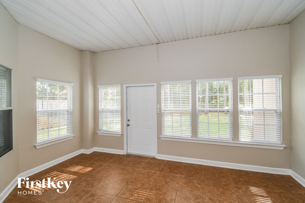 an empty living room with a white door and windows