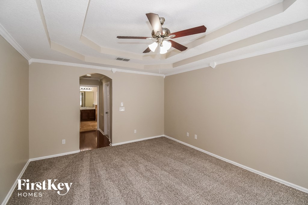 a empty living room with a ceiling fan and carpet