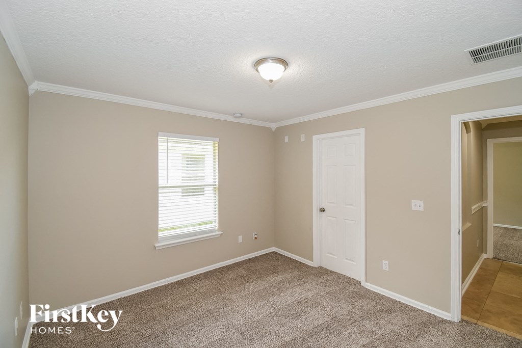 a bedroom with a door and a window and a carpeted floor