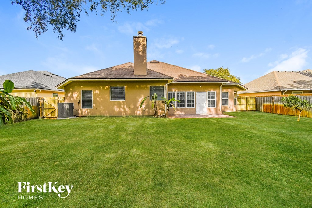 a backyard with a yellow house and a green lawn
