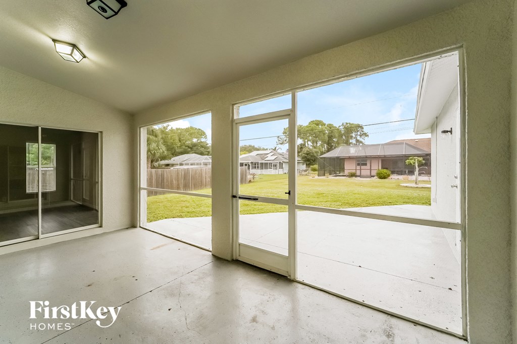 a view of the yard from the inside of a house with large glass doors
