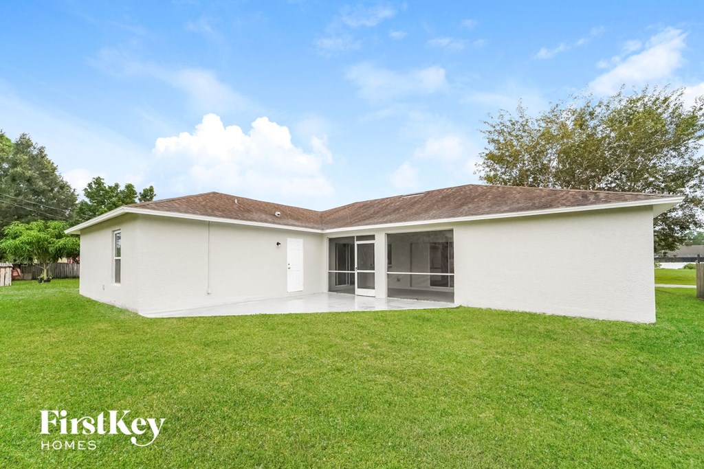the backyard of a white house with a green lawn