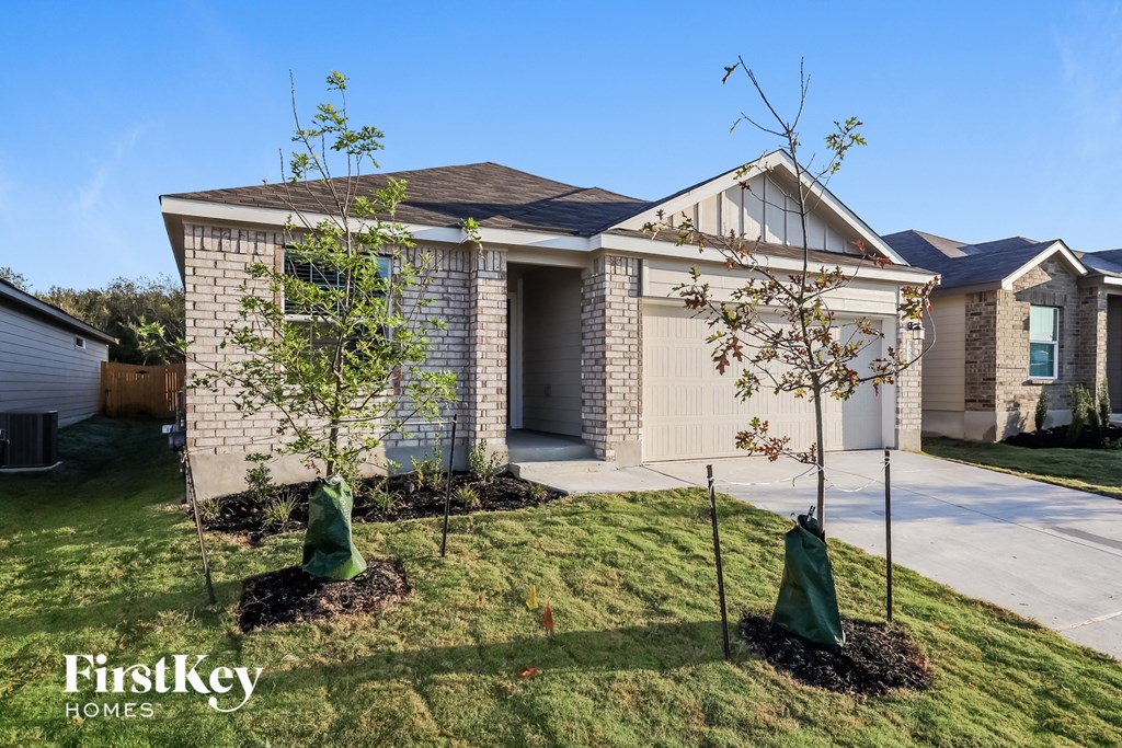 A house with a brown brick exterior and a garage door is for sale.