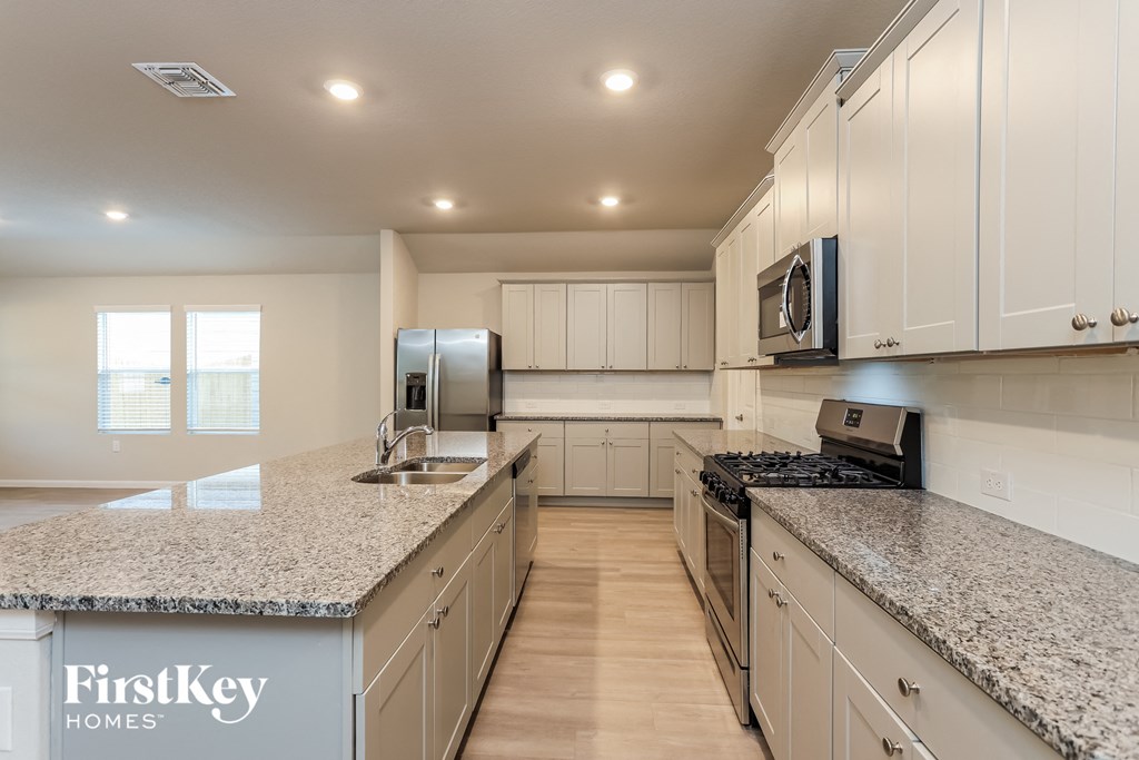 A kitchen with granite countertops and white cabinets.