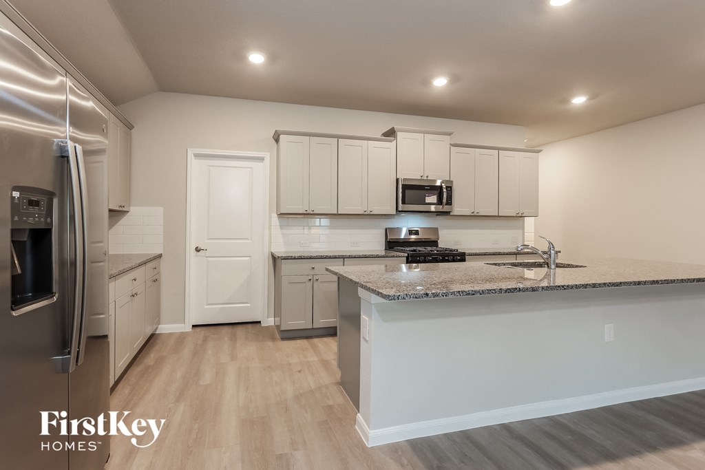 A kitchen with a refrigerator, microwave, and cabinets.