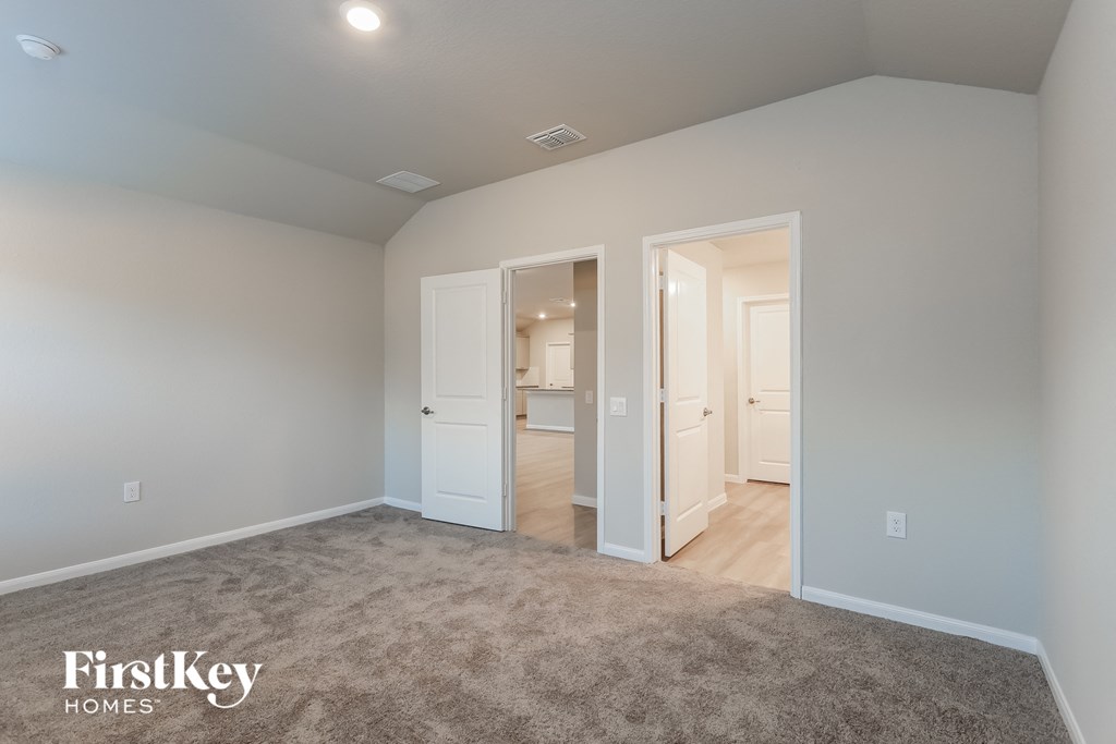A spacious room with a carpeted floor and two open doors leading to other rooms.