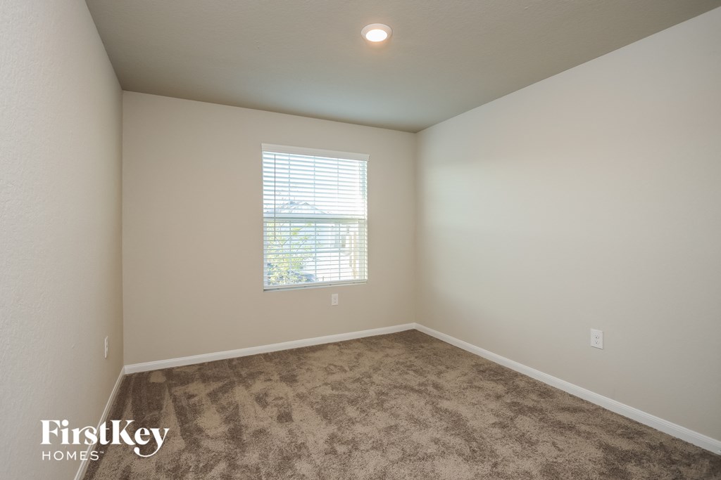 A room with a carpeted floor and a window with blinds.