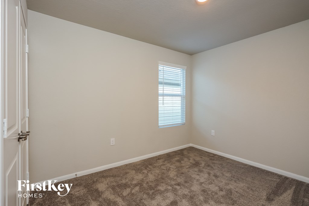 A room with a carpeted floor and a window with blinds.