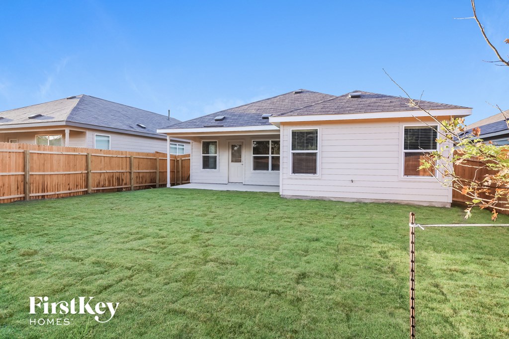 A backyard with a fence and a house.