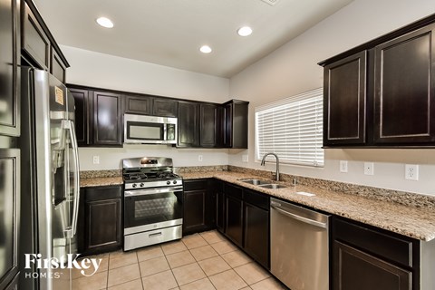 a kitchen with black cabinets and granite counter tops and stainless steel appliances