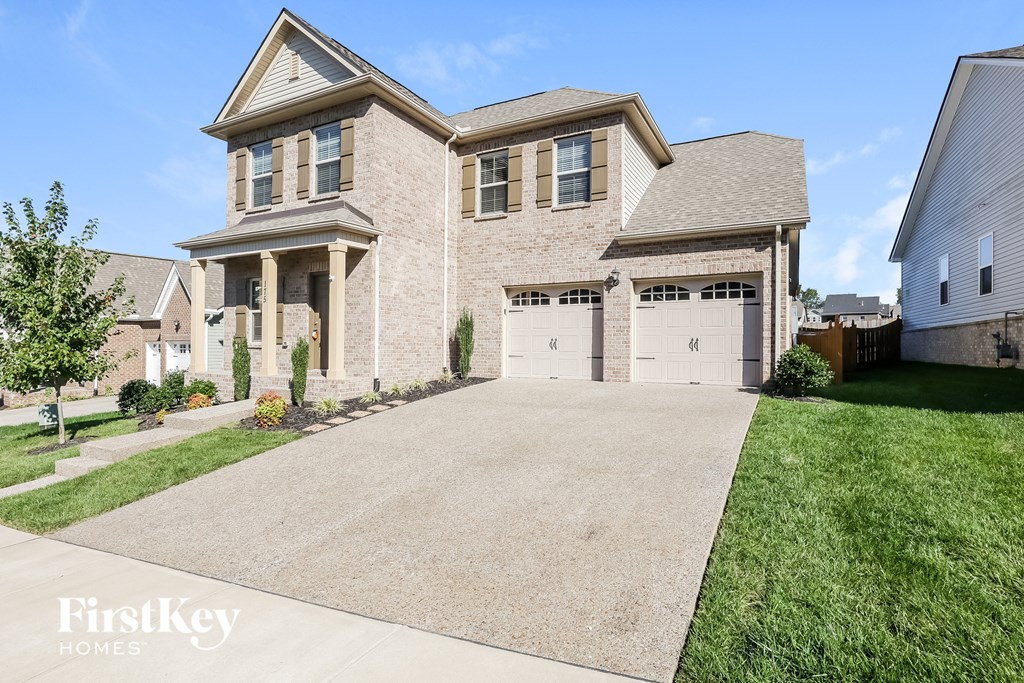 a large brick house with a driveway and garage doors