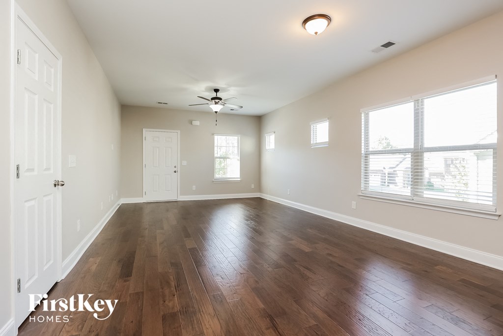 an empty living room with hardwood flooring and a ceiling fan