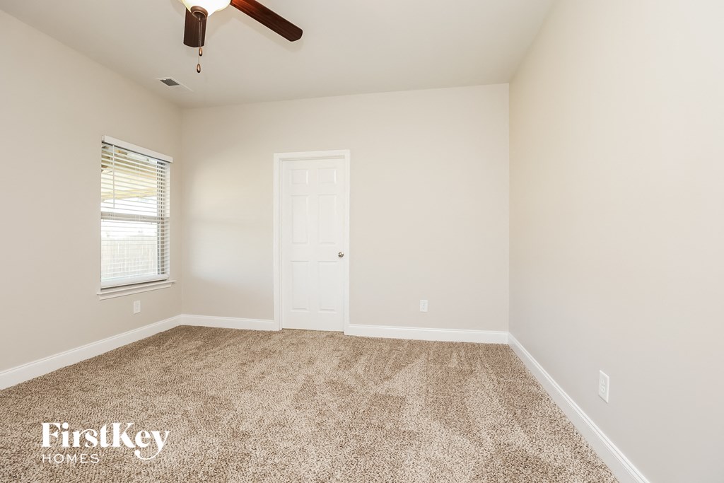 a bedroom with carpet and a white door and a window