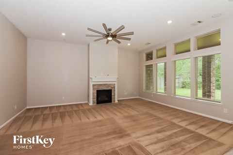 an empty living room with a fireplace and a ceiling fan