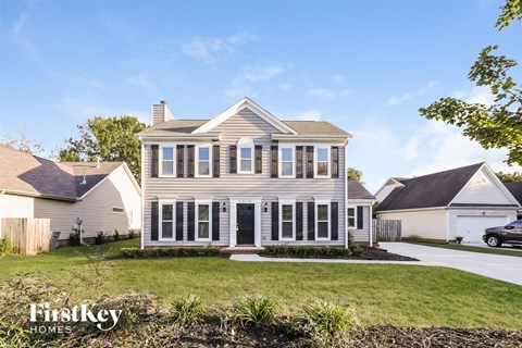 A house with a white picket fence and a car parked in the driveway.