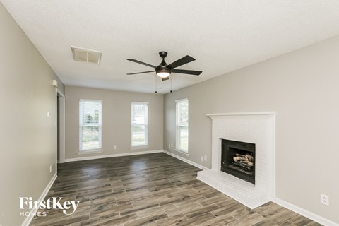 A spacious room with a fireplace and a ceiling fan.
