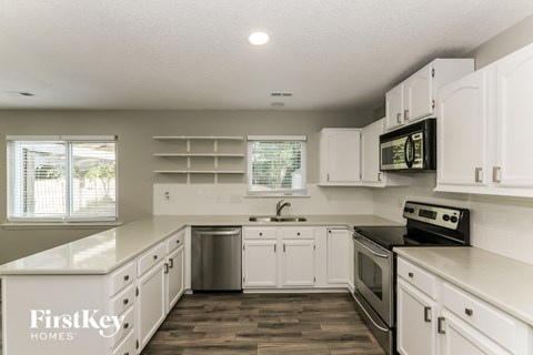 A kitchen with white cabinets and a wooden floor.