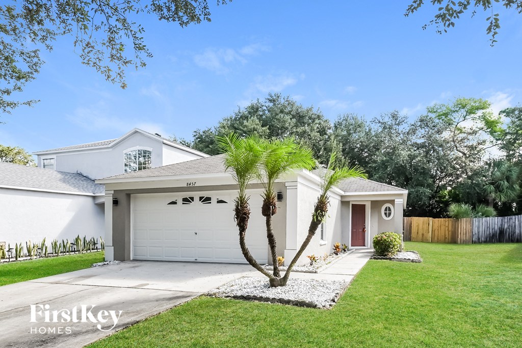 a white house with a lawn and palm trees