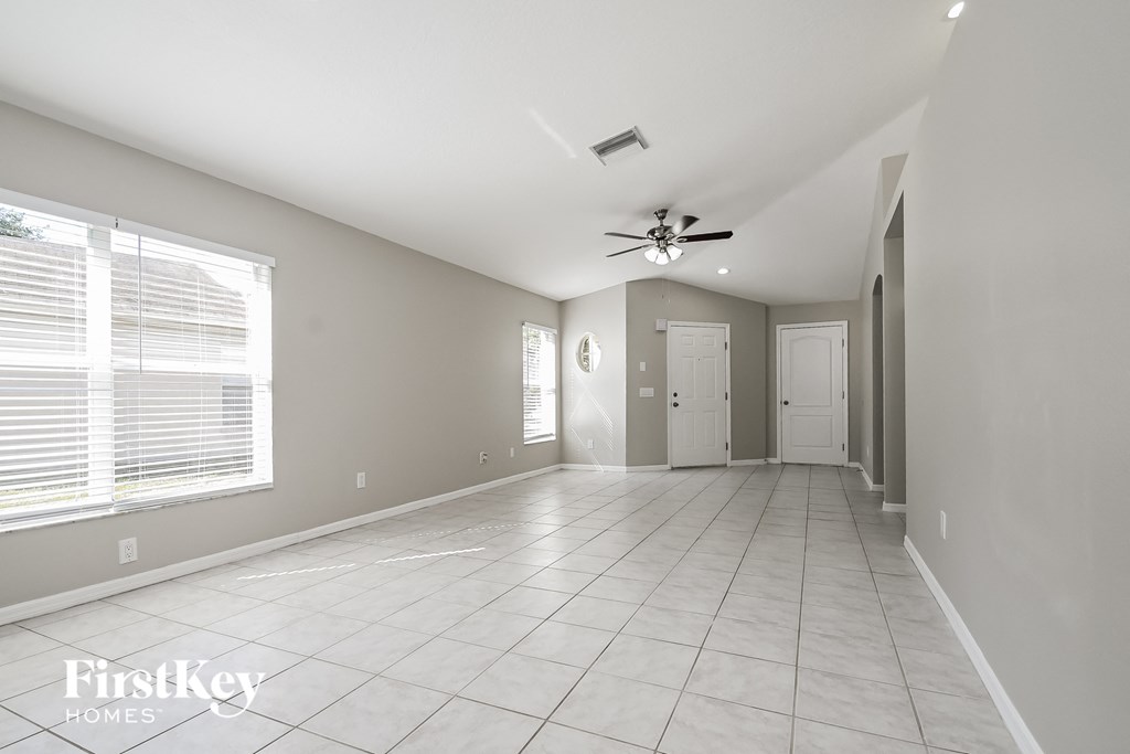 an empty living room with a ceiling fan and a tiled floor