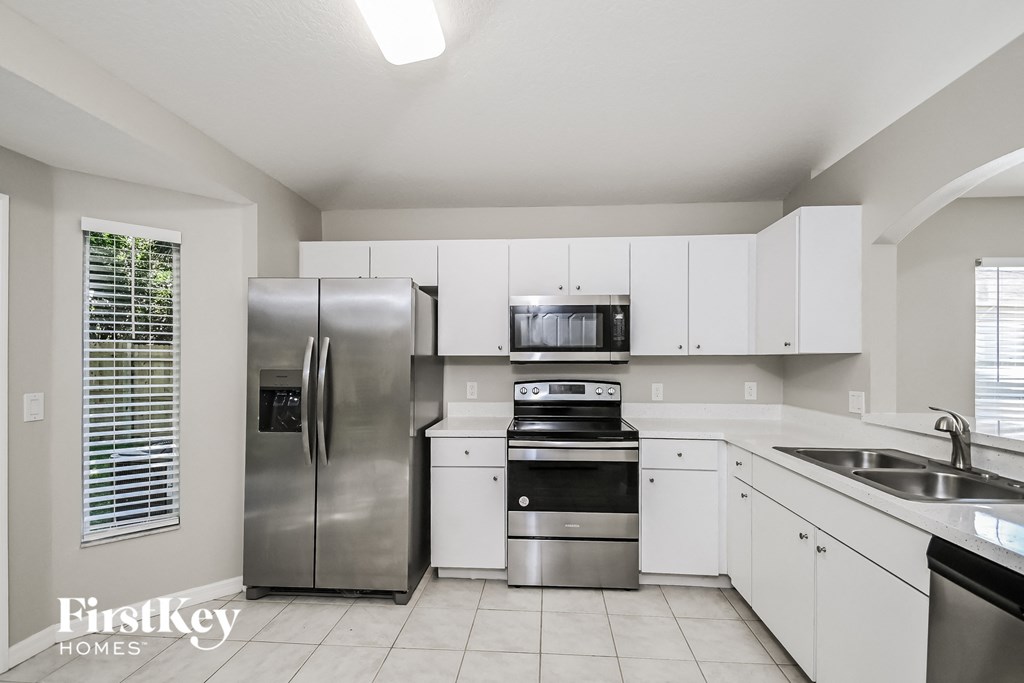 a white kitchen with stainless steel appliances and white cabinets