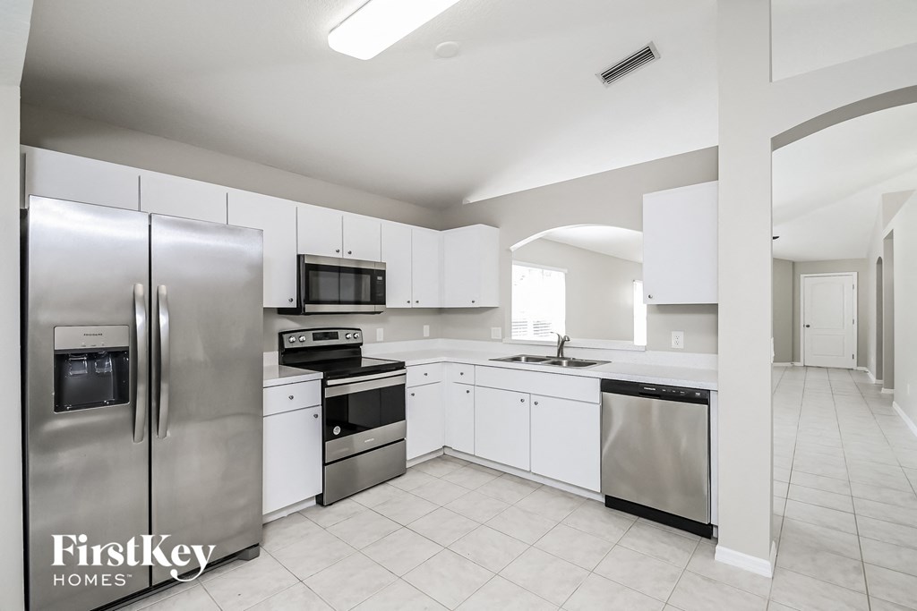 a white kitchen with stainless steel appliances and white cabinets