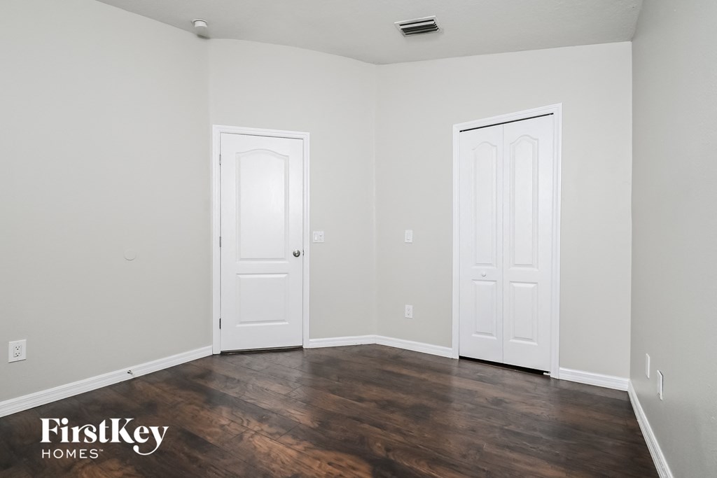 a bedroom with white walls and white doors and wood floors