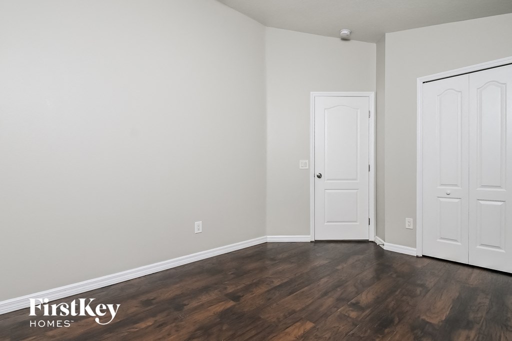 a bedroom with white walls and wooden floors and two doors