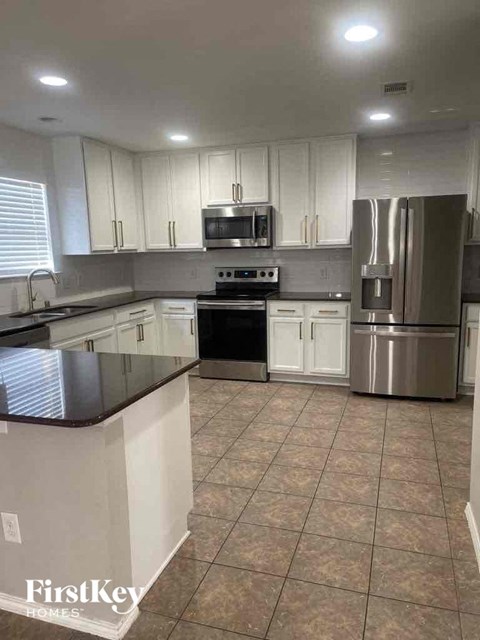 A kitchen with white cabinets and a black countertop.