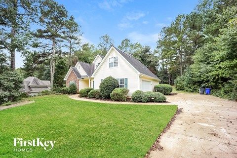A house with a well-maintained lawn and trees in the background.