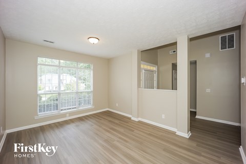 A room with wooden floors and a window with blinds.