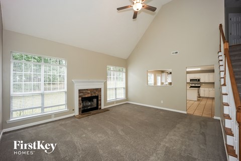A spacious living room with a fireplace and a staircase.