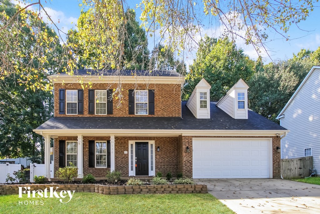 a brick house with a black roof and a white garage