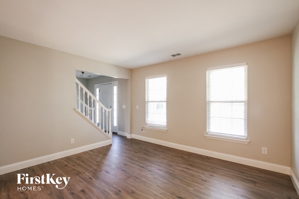 an empty living room with wood floors and a staircase