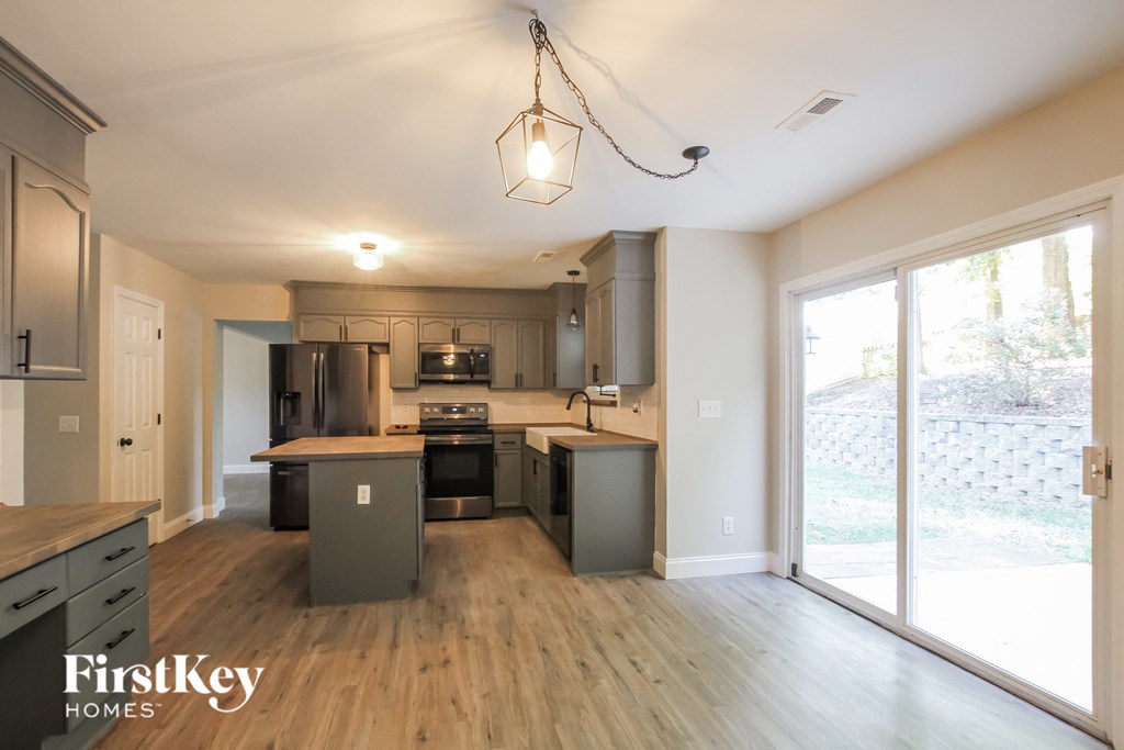an open kitchen with wood flooring and a large window