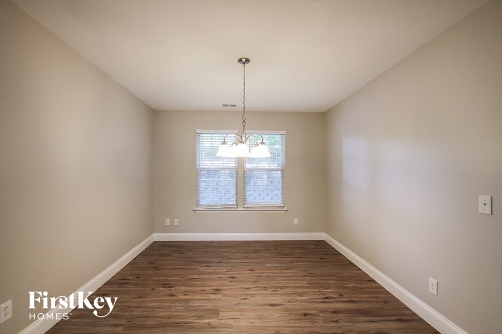 an empty dining room with wood floors and a chandelier