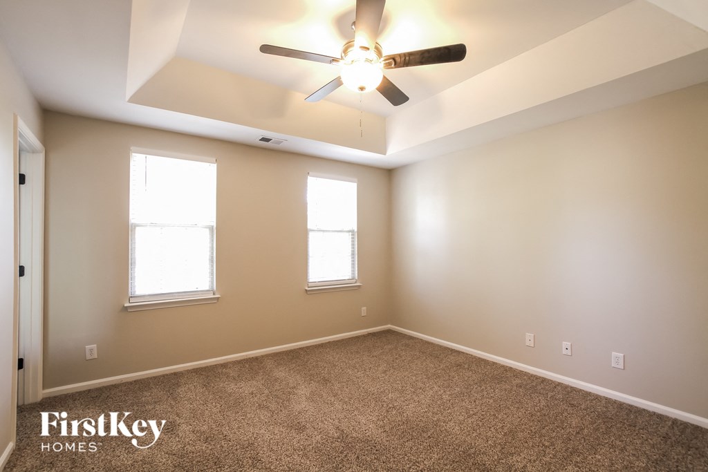 an empty room with a ceiling fan and two windows