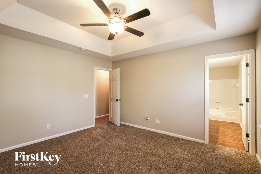 a living room with a ceiling fan and a door to a bathroom