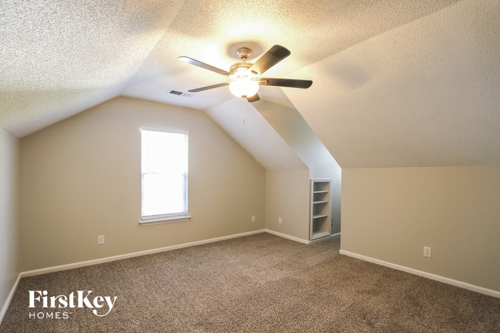 the bonus room is spacious with carpet and a ceiling fan